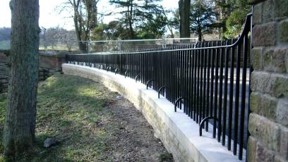 Black Wrought iron fencing in woodland garden